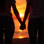 Young couple holding hands on a beach at sunset