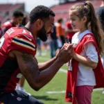 A football player patiently signs an autograph for a young female fan