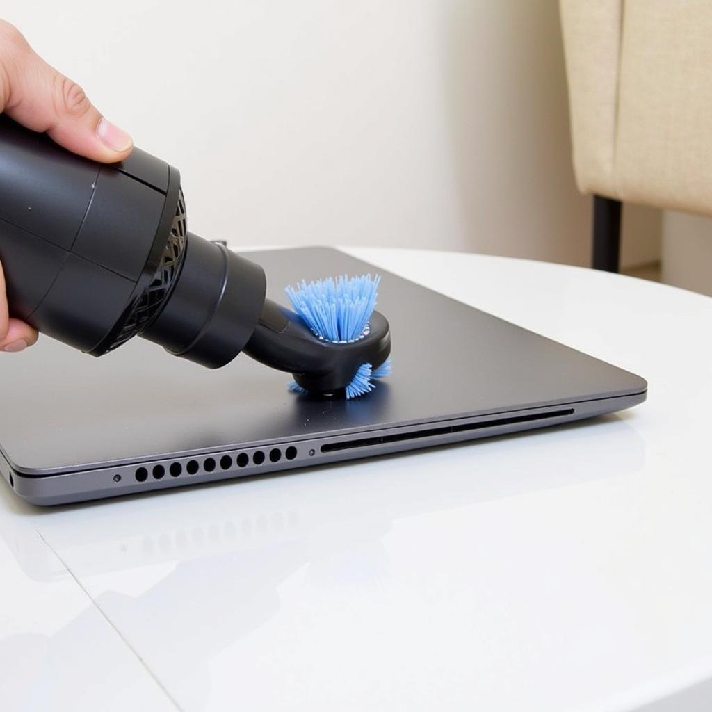 Using a vacuum cleaner with a brush attachment to clean laptop vents