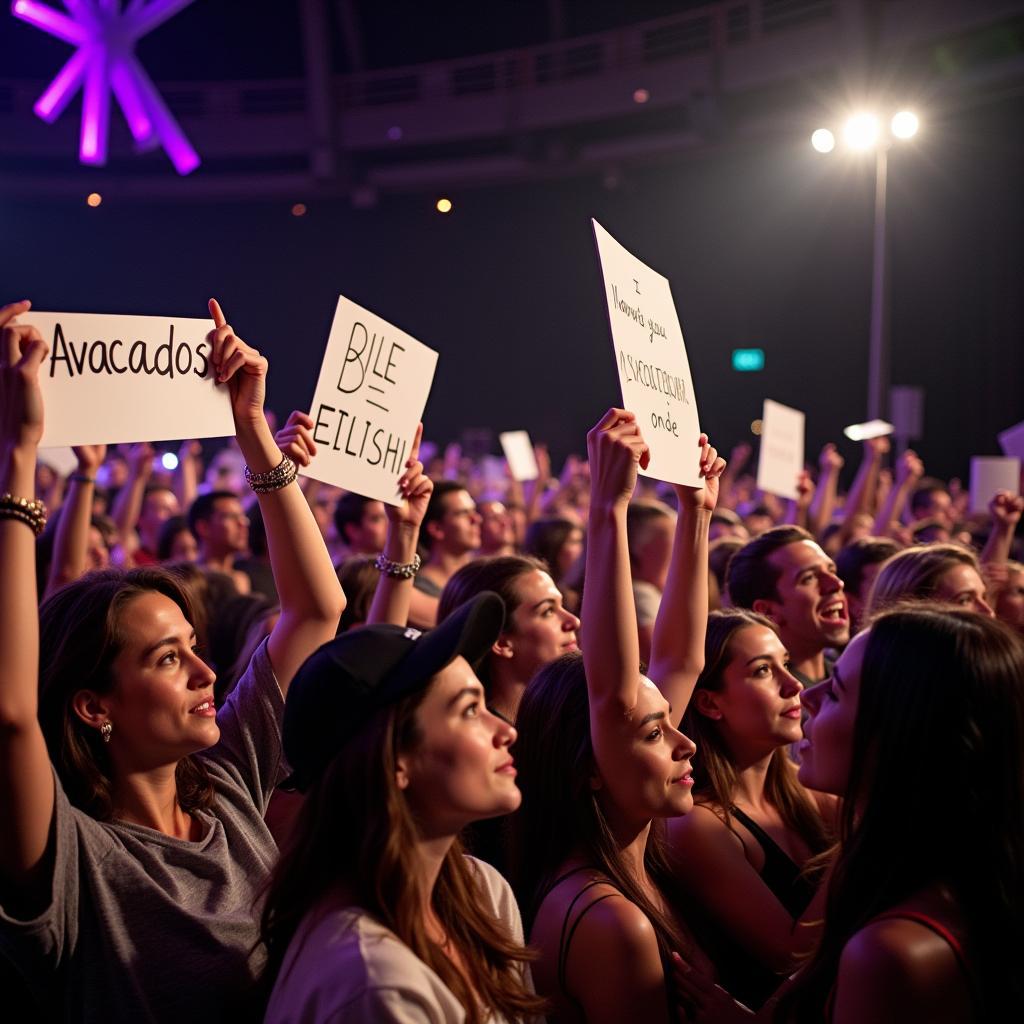 Billie Eilish fans holding up signs with "Avacados" written on them at a concert.