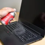 Cleaning a laptop cooling pad with compressed air.